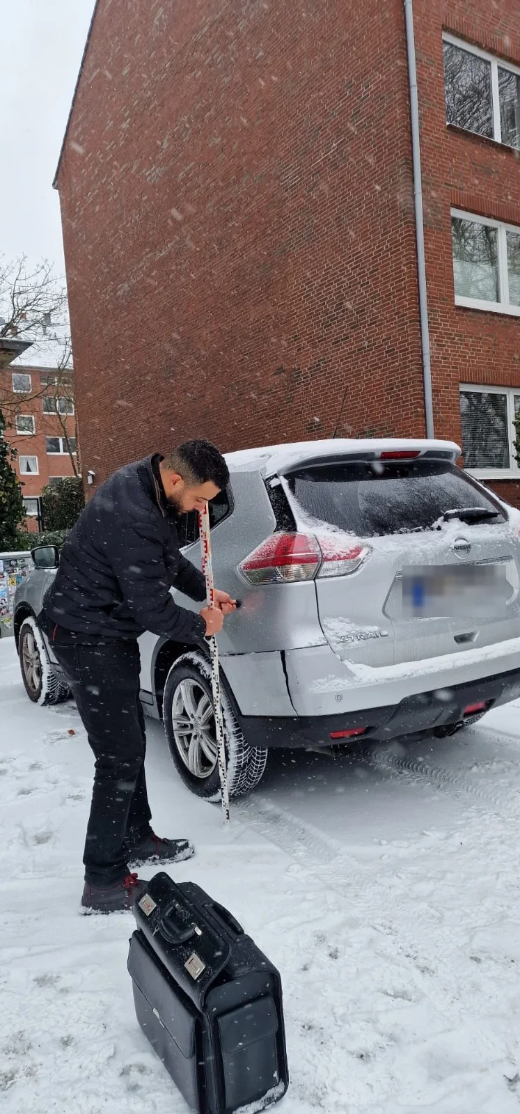 Kfz-Gutachter in Hamburg bei der Schadenaufnahme mit Messlatte am Heck eines Pkw